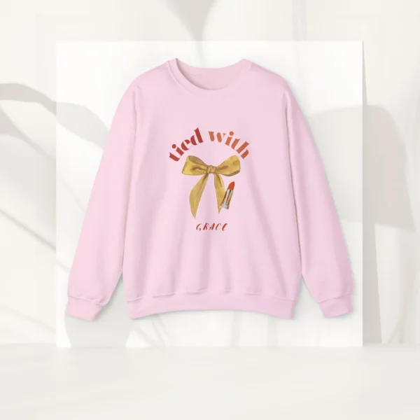 Tied with grace sweatshirt with bow and lipstick design on Gildan 18000 - Light Pink Flatlay
