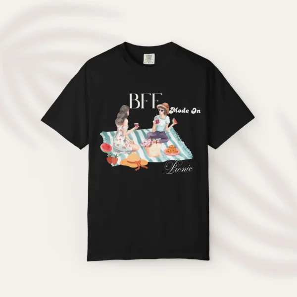 BFF Mode On Tee with watercolor illustration of two girls enjoying a picnic with fruit, waffles, a basket & drinks on striped blanket on Comfort Colors 1717 - Black Flatlay