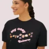 My Cozy Universe Tee with books, candle, couch, bow design on CC3023 - Black Closeup
