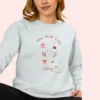 Sweatshirt with “You Look Like Poetry Today” quote and soft illustrated aesthetic elements like perfume, lipstick, ribbons, and hearts - Chambray
